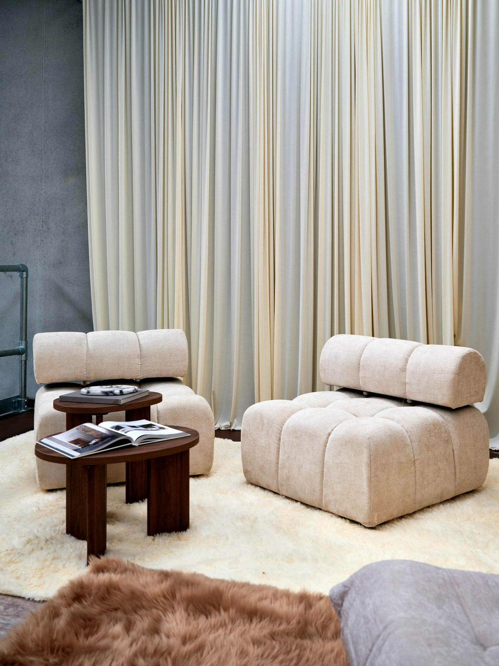 Fauteuils modulaires crème devant des rideaux