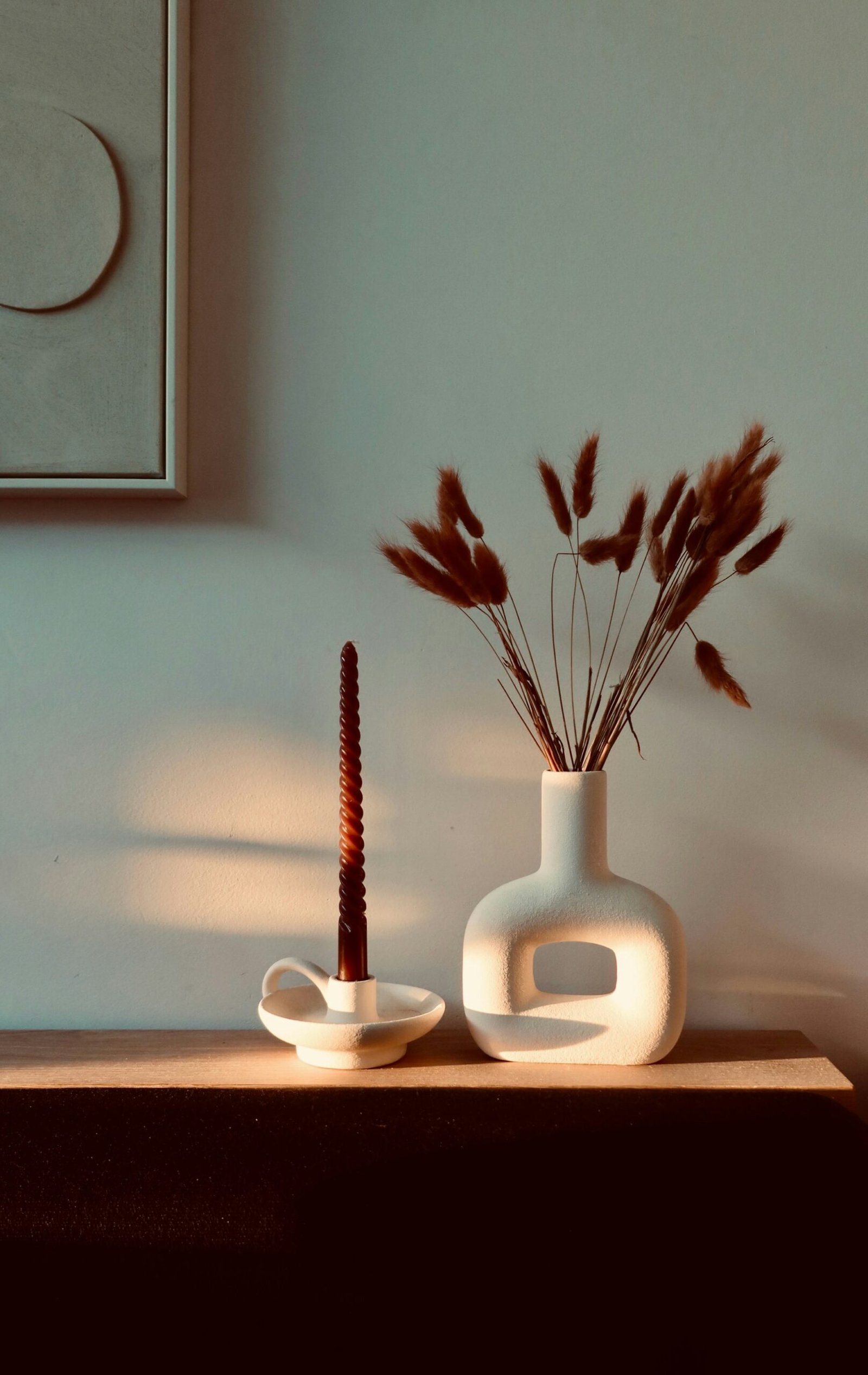 Vase en céramique blanche et fleurs séchées sur une console